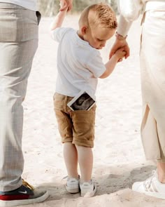 a little boy is holding the hand of his mother