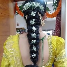 the back of a woman's head with braids and flowers in her hair