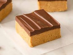 three pieces of chocolate peanut butter bars sitting on top of white parchment paper next to coffee beans