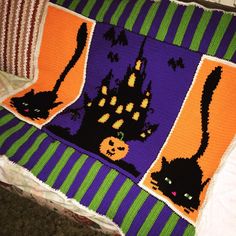 a crocheted blanket with black cats and pumpkins on it