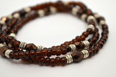 Coffee Brown Seed Bead and Silver Boho Stretch Bracelet Set of 3 Bracelets  These dainty bracelets are made with Preciosa glass seed beads 6/0 which are about 4mm in size, Preciosa fire polished Czech glass beads 6mm, and silver filled spacer beads about 3mm in size. The seed beads are a deep coffee brown and the fire polished beads are a dark bronze. Beautiful bracelet set for someone who loves earth tones. Each bracelet is made with stretch elastic knotted five times, secured with hypo cement glue for added strength. Bracelets shown in picture are 7 inches. If you would like a custom size not listed please select 0 inches and add a note with your requested size in inches. For a snug fit order a half inch up, and for a loose fit order one inch up from your wrist size. Stretch elastic allo Boho Earth Tones, Unique Beaded Jewelry, Mocha Coffee, Handmade Jewelry Bracelets, Dainty Bracelets, Coffee Brown, Seed Bead Bracelets, Layered Bracelets, Fabric Bag