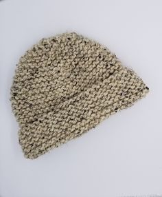 a knitted hat laying on top of a white surface