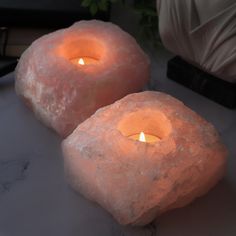 two candles are sitting on top of some rock like objects that look like they have been made out of ice