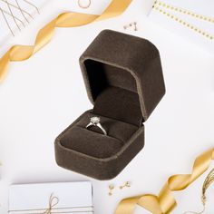 an open ring box sitting on top of a table next to gold ribbons and confetti