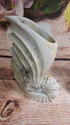 a white vase sitting on top of a wooden table