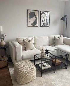 a living room with white couches and two pictures hanging on the wall above them