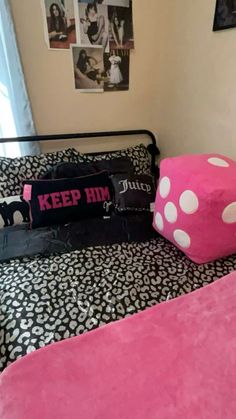 a pink pillow sitting on top of a bed next to a black and white bedspread