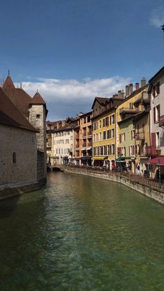 a river running through a city with tall buildings on both sides and people walking along the side