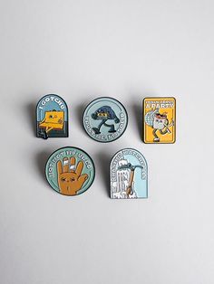 four pin badges with words describing the different types of animals and their names on them