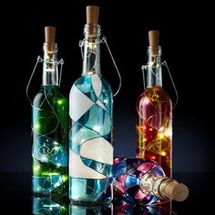 three bottles with lights in them on a reflective surface, one is empty and the other has a cork