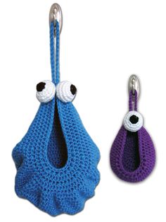 two crocheted purses with eyes hanging from hooks on each side, one blue and the other purple