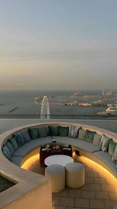 an outdoor seating area on top of a building overlooking the water and cityscape