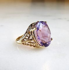 "This is a vintage 10K yellow gold filled filigree ladies ring. It is set with a large oval amethyst gemstone. The stone measures 11.9mm x 15.9mm. There is a natural inclusion in the amethyst that you will see throughout the pictures. The band is sized at a 7. Total weight of the ring is 5.3grams/3.4dwt. The band is stamped 10K inside. There is a hallmark that is an \"F\" inside a diamond shape. This is a vintage, previously owned ring. Therefore, light wear can be expected. There is no visible Ornate Oval Amethyst Ring, Oval Amethyst Ring With Filigree Detail, Oval Amethyst Filigree Ring For Wedding, Purple Oval Filigree Rings, Wedding Oval Amethyst Ring In 14k Gold, Vintage Oval Amethyst Ring With Filigree, Vintage 14k Gold Amethyst Ring With Accent Stones, Ornate Oval Amethyst Gemstone Ring, Oval Filigree Ring With 17 Jewels For Anniversary