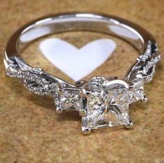 a heart shaped diamond ring sitting on top of a table