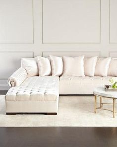 a living room with a white couch and coffee table in front of a large wall