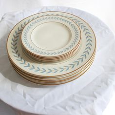 a stack of white and blue plates sitting on top of a white cloth covered table