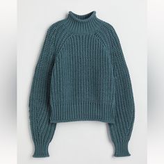 a green sweater hanging up on a white wall, with the top half turned down