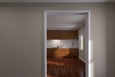 an open door leading to a kitchen with wood flooring and white brick wall in the background