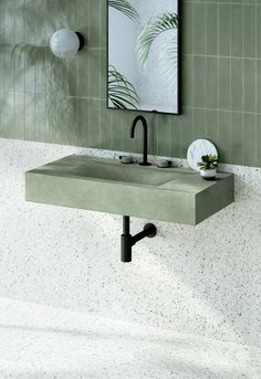 a bathroom sink sitting under a mirror next to a wall mounted faucet in front of a green tiled wall