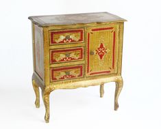 an ornately painted chest of drawers with gold and red paint on the doors, in front of a white background