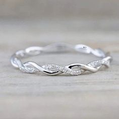 a white gold wedding band with diamonds on the side, sitting on a wooden surface