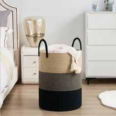 a black and white basket sitting on top of a wooden floor next to a bed