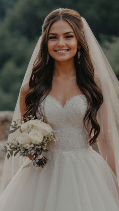 a woman in a wedding dress holding a bouquet and smiling at the camera with her veil over her head