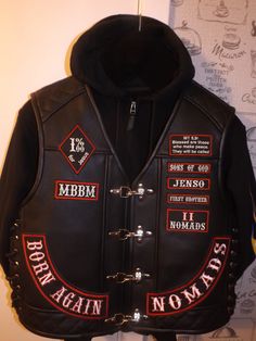 a black leather jacket with patches and words on the back, attached to a wall