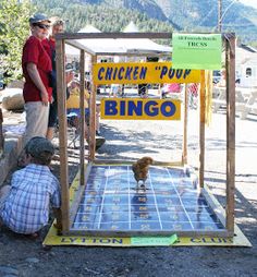 two men are looking at a chicken poop game on the ground with mountains in the background