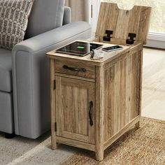 a wooden table with an electronic device on it next to a gray couch in a living room