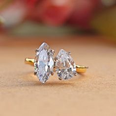 two pear shaped diamond rings sitting on top of a table