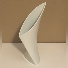 a white vase sitting on top of a table next to a brown wall and floor