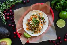 a tortilla filled with meat and vegetables on top of a table next to cranberries