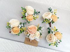 small bouquets of flowers are arranged on a white table cloth with a name tag