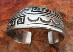 HEFTY NAVAJO BRACELET, Signed by renowned Navajo Artist, Dan Jackson whose hallmark "JACKSON" in a Hogan is stamped inside. It is deeply stamped and chiseled with Navajo Sunburst symbols and overlay Wave Curl symbols. Solid thick Sterling Silver6 1/2" inside circumference including a 1" gap opening. Very thick and solid silver likely not adjustable7/8" Wide79.77 GramsPre-owned in excellent condition. Some Patina. But no damage Jerry Garcia Band, Navajo Bracelet, Cluster Bracelets, Beaded Cuff Bracelet, Royston Turquoise, Onyx Bracelet, Beaded Cuff, Vintage Turquoise, American Jewelry