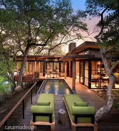 an outdoor living area with two green chairs next to a swimming pool and wooden deck