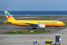 a large yellow airplane is on the runway at an airport with other vehicles around it