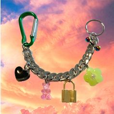 a keychain with charms attached to it in front of a cloudy sky and pink clouds