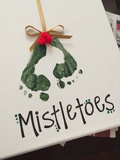 a handprinted christmas card with the word mistle toes on it and a ribbon