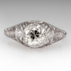 Circa 1920s domed ring features a pierced design and is centered with one (1), bezel set, old European cut diamond. The gallery is accented with six (6), bead set, round single/Swiss cut diamonds. The ring measures 9.8mm at the top, rises 7.0mm above the finger, tapering to 2.0mm wide and 1.2mm thick at the base of the shank. Platinum Art Deco Ring With Bezel Setting, Classic Domed Diamond Ring, Art Deco Diamond White Ring With Bezel Setting, Art Deco White Diamond Ring With Bezel Setting, Antique Diamond Ring With Bezel Setting, Art Deco White Gold Diamond Ring With Bezel Setting, Art Deco Diamond Ring With Bezel Setting, Vintage Diamond White Ring With Bezel Setting, Vintage White Gold Diamond Ring With Bezel Setting