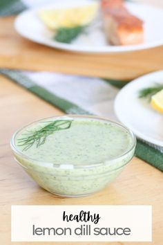 a bowl of lemon dill sauce sitting on a table next to plates of food