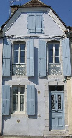 an old house with blue shutters on the front and side windows that are open