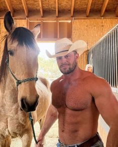 a shirtless man standing next to a horse