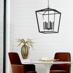 a dining room table with two chairs and a vase filled with candles on top of it