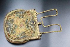 DESCRIPTION: This antique purse from the 1850's exudes elegance and charm. The stunning embroidered body is a work of art, featuring delicate and intricate foliage in various shades of green and brown, creating a forest-inspired motif. The gilded frame adds a touch of glamour to the purse, with blue glass and faux pearls meticulously placed to enhance its beauty. The frame is in excellent condition and functions smoothly with a push-pull lock mechanism. The purse shows normal wear and patina, wh Antique Gold Embroidered Bags, Antique Embroidered Evening Bags, Victorian Style Gold Embroidered Bag, Vintage Formal Bag With Floral Embroidery, Vintage Floral Embroidery Bags For Formal Occasions, Vintage Floral Embroidery Formal Bags, Vintage Floral Embroidered Bag For Formal Occasions, Victorian Embroidered Evening Bags, Vintage Wedding Bags With Gold Embroidery