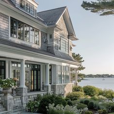 a large house with lots of windows next to a body of water