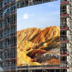 a large building with scaffolding around it and mountains in the backround