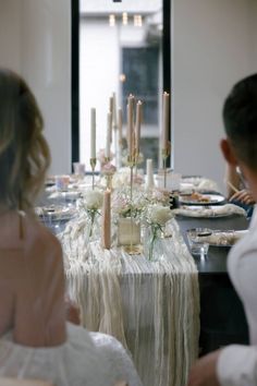 a woman sitting at a table in front of a man with candles on the table