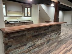 an empty kitchen and living room with wood flooring on the walls, counter tops and cabinets