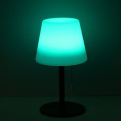 a lamp that is lit up in the dark with a green light on it's side